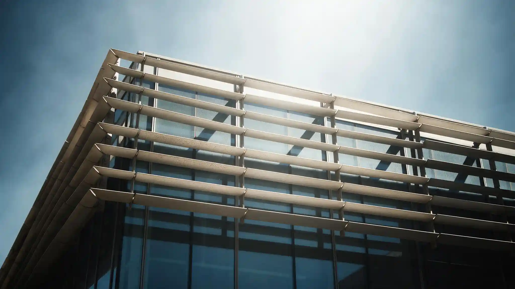 Exterior motorised shading louvres on a commercial building facade under strong Gulf daylight